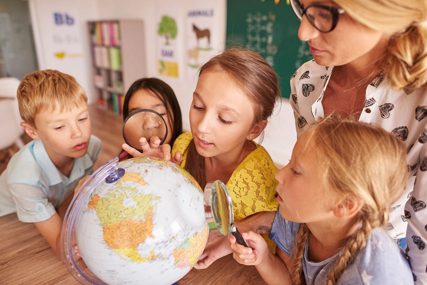 Children and teacher examining a globe in a classroom setting