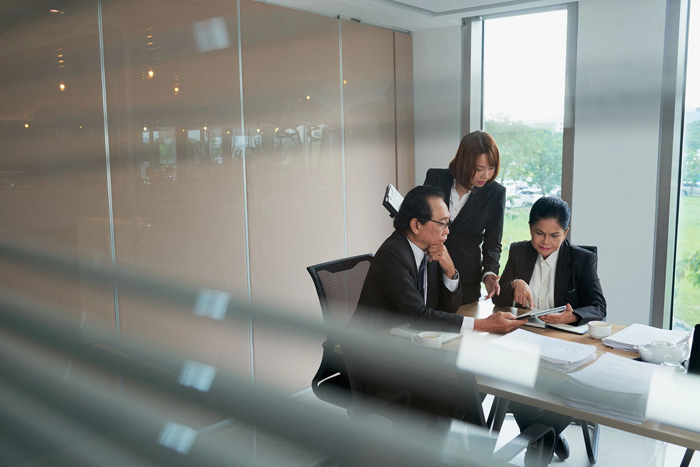 A personal secretary and businessman standing by a conference table, reviewing documents together in a bright Singapore office.