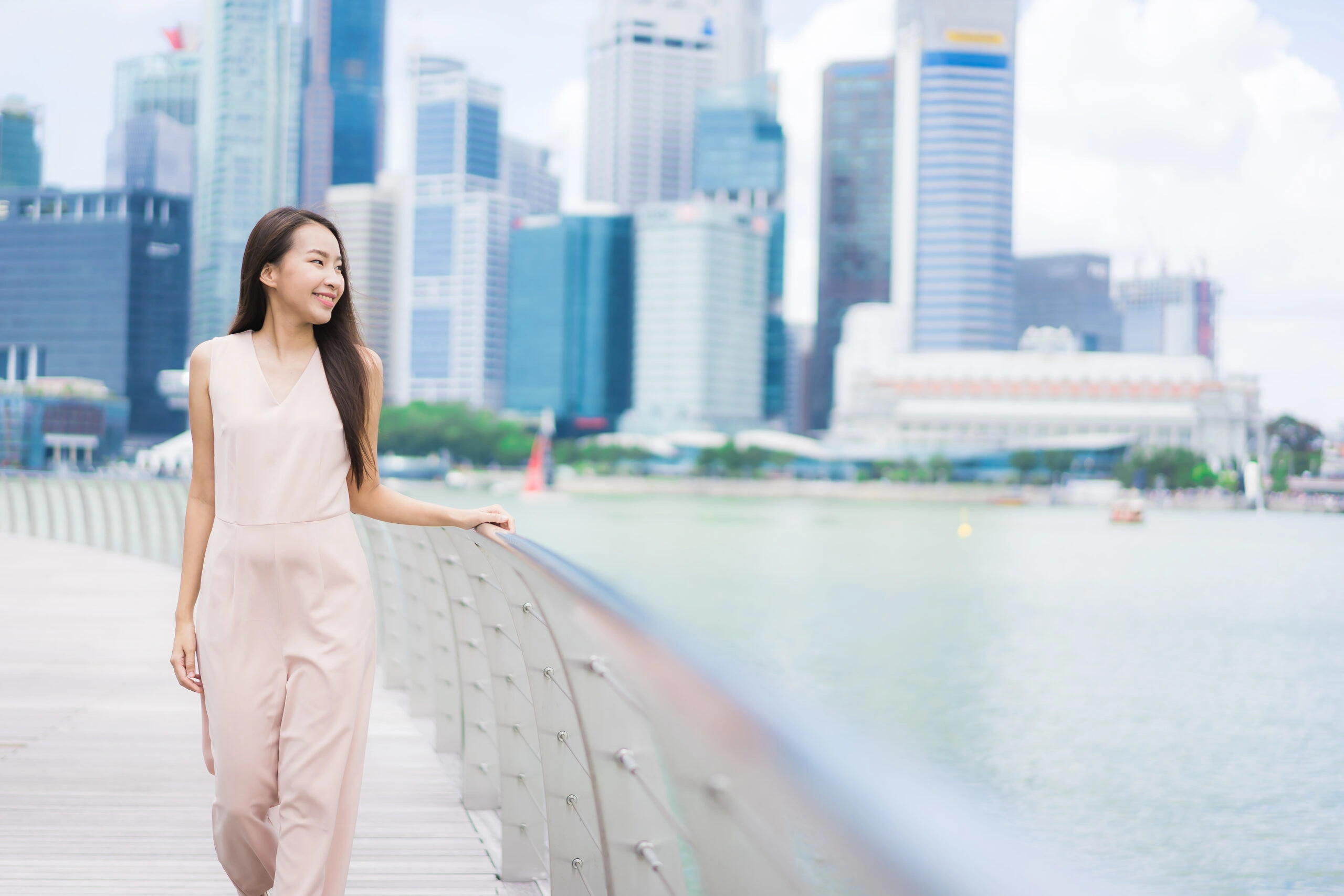 Happy woman smiling with Singapore skyline in the background after gaining Singapore citizenship.