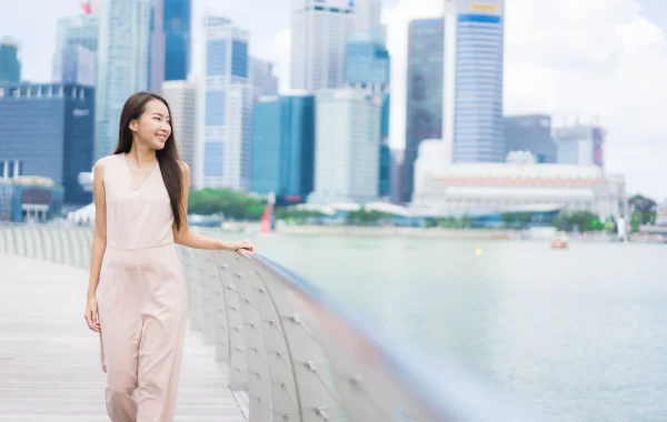 Happy woman smiling with Singapore skyline in the background after gaining Singapore citizenship.