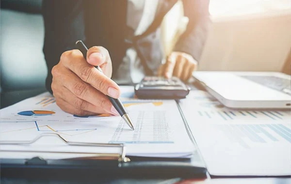 Professional working on financial calculations and signing tax documents for a client, representing Singapore accounting and tax services by Yobbi